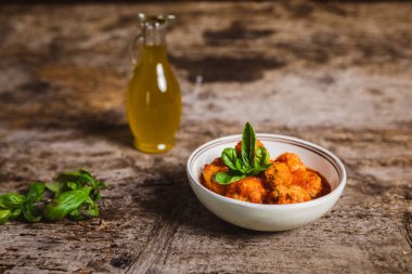 Domates soslu köfte kasede ve ahşap masada zeytinyağı.