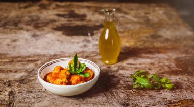 Domates soslu köfte kasede ve ahşap masada zeytinyağı.