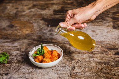 Şef, domates soslu köfteli kaseye zeytinyağı döktü.