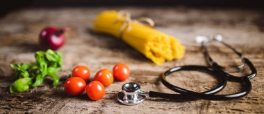 Tahta bir masada kiraz domatesli, soğanlı ve steteskoplu sarı uzun spagetti. Sarı İtalyan makarnası. Çiğ spagetti..