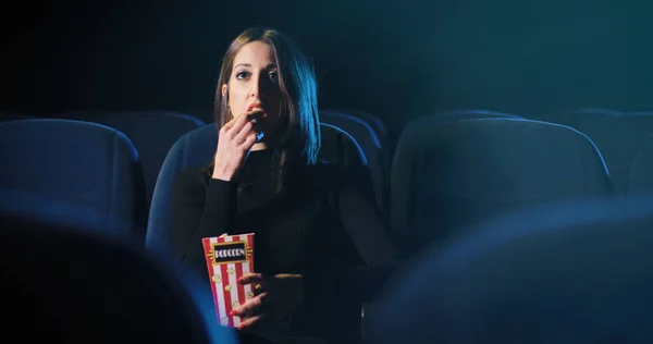Closeup portrait of beauty young Italian woman sitting in cinema with box of popcorn