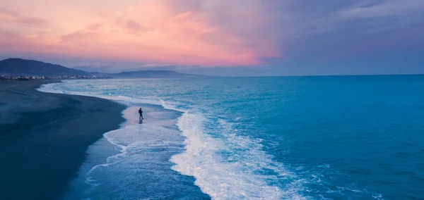 Gün batımında sahilde yürüyen bir adam 