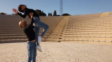 Gün ışığında açık hava tiyatrosunda birkaç güzel dansçı. Genç bir kadın gündüz vakti genç bir adamla dans ediyor. 