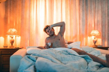 Evde bir fincan kahveyle yatan genç adamın portresi. 