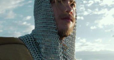 Gündüz vakti okyanus kıyısında ata binen Viking. 