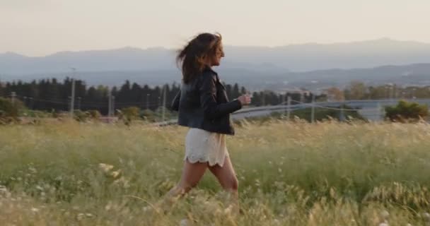 Junges Mädchen Weißen Shorts Und Schwarzer Lederjacke Spaziert Bei Sonnenuntergang — Stockvideo