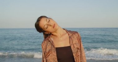 Siyah çizmeleri ve beyaz pantolonu olan güzel İtalyan kız yazın deniz kenarında dans eder.