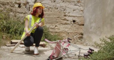 Outdoor footage of beauty Italian architect in yellow helmet. Young woman with rolled blueprints in construction side at daytime 