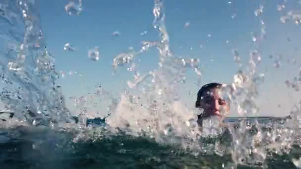 Vrouw Een Blauwe Bikini Spat Zeewater Met Haar Handen — Stockvideo