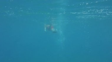 Genç adam denizde yüzüyor. Su altı görüntüsü