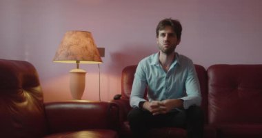 duygusal genç adam kanepede oturuyor ve televizyon izliyor.