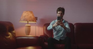 Evde akıllı telefondan video görüşmesi yapan yakışıklı genç adam.