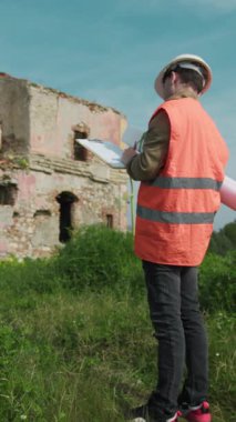 İnşaat alanındaki mühendis eski binaya bakıyor ve notlar alıyor.. 