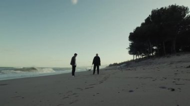 Kıdemli Centilmen ve Bakıcının Silueti Gün Doğumu Okyanusu 'nda Sahilde Yürüyor.