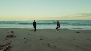 Öğleden sonra okyanus manzarasını yüksek dalgalarla izleyen iki adamın silueti..