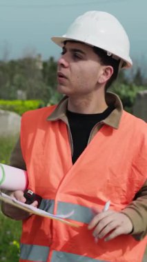 Mimar inşaat sahasında yürürken not alıyor ve etrafa bakıyor..