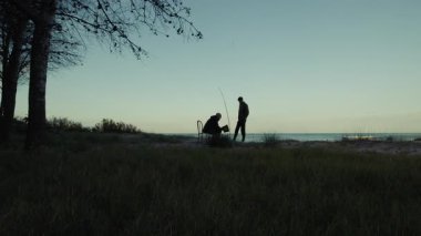 İki balıkçının silueti sabırla balığın şafakta ısırılmasını bekliyor..