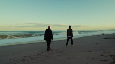 Sabah saatlerinde Doğa Sahilinde Yürüyen İki Adamın Silüeti.