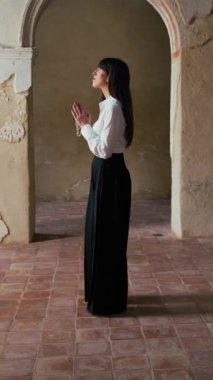 Eski bir kilisenin ortasında durmuş dua eden bir kadın. . 