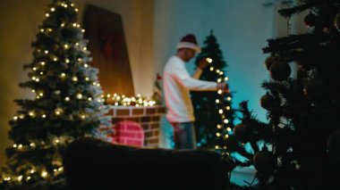 Adam otel odasındaki Noel Işıklarını Ağaca Tutuyor.