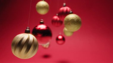 Noel Baloları Kızıl Arkaplan 'daki büyüleyici sarkaçlar gibi sallanıyor.