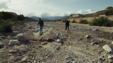 Erkekler kuraklık nedeniyle kurak bir nehirde yürür..