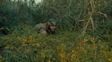 Bir asker, düşmanı daha iyi gözlemlemek için çayırda sürünür..