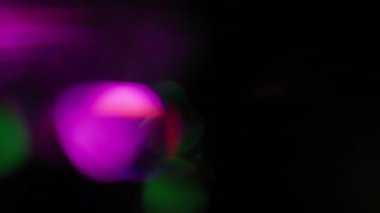 Siyah Arkaplanda Parlayan Yeşil ve Mor Işık Sızıntıları.