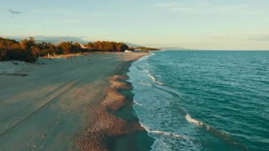 Rahatlayan okyanus dalgaları kumlu kumsala vuruyor gün batımında, düğün arka planında.