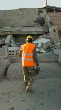 Kasklı bir işçi terk edilmiş ve yıkılmış bir binaya bakar..