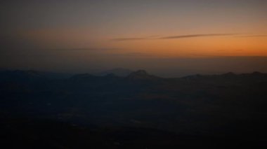 Gün batımında dağ siluetleriyle altın saat gökyüzü.