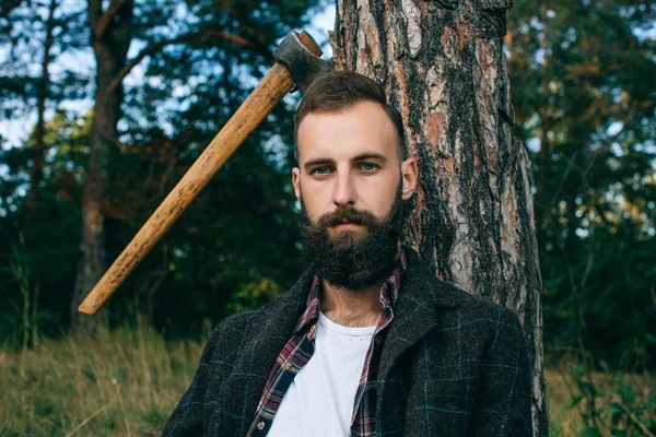 Портрет жорстокий бородатий і гострий дерев'яний хіпстер Циганський чоловік в лісі з сокирою — стокове фото
