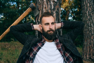Portre acımasız sakallı ve bıyıklı oduncu hipster çingene adam ormanda balta ile