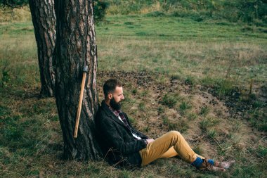 Portre acımasız sakallı ve bıyıklı oduncu hipster çingene adam ormanda balta ile