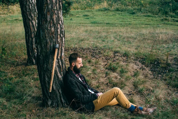 Portrait brutal bearded and moustached woodcutter hipster Gypsy man in the forest with ax — Stock Photo, Image