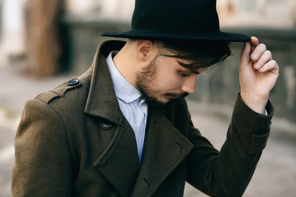 スーツケースが付いている通りの Fedora 帽子でハンサムな若いひげを生やしたヒップスター男男。レトロなビンテージのファッションを見て — ストック写真