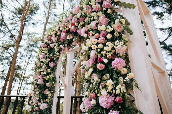Arch for the wedding ceremony, decorated with fresh flowers in a pine forest — Stock Photo, Image