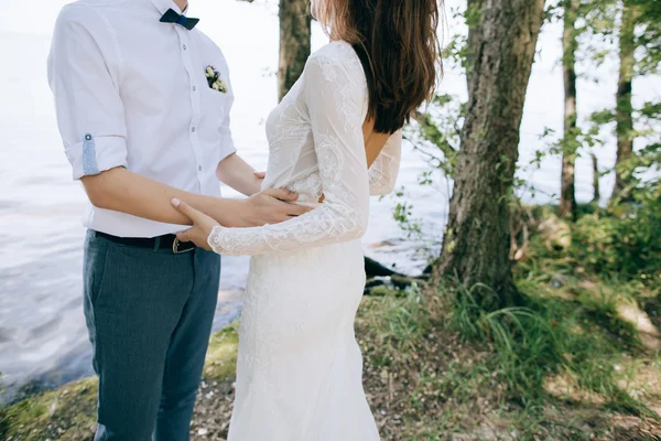 Bruden och brudgummen embracing vid havet — Stockfoto