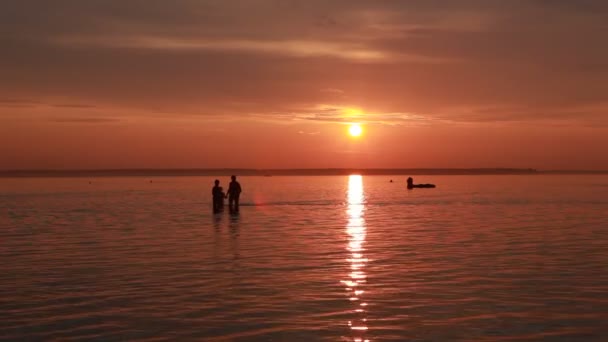 Sziluettjét az emberek és a hajó sunset tengerparton — Stock videók