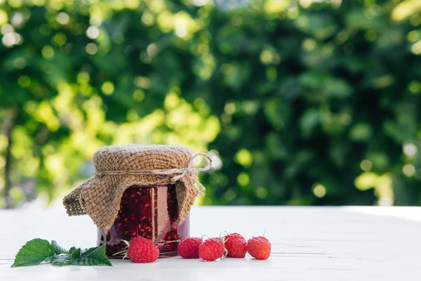 Hem- gjort Hallon sylt i en burk på träbordet i trädgården — Stockfoto