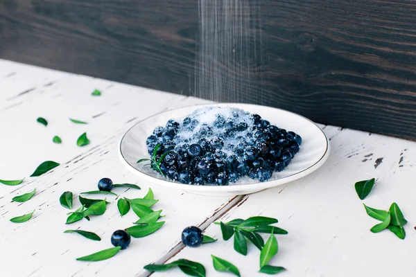 Top view of fresh wild blueberries  with sugar on wood background