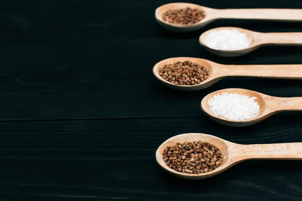 Riso e semole di grano saraceno nel cucchiaio di legno sul tavolo nero — Foto Stock