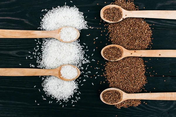 Riso e semole di grano saraceno nel cucchiaio di legno sul tavolo nero — Foto Stock