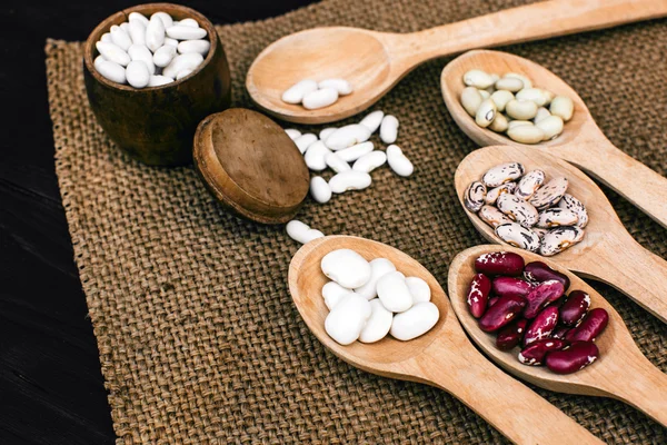 A colorful of beans in wood spoon on wood background