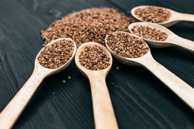 karabuğday kabuğu çıkarılmış tane ve siyah masada tahta kaşık