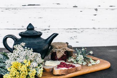 Ahududu reçeli ve bir kavanoz ve ahşap masa yemek kahvaltı sıcak bitkisel çay tereyağlı ekmek