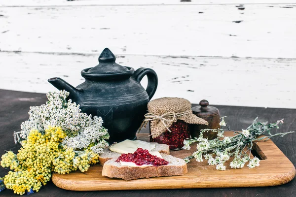 Ahududu reçeli ve bir kavanoz ve ahşap masa yemek kahvaltı sıcak bitkisel çay tereyağlı ekmek — Stok fotoğraf