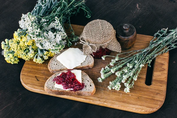 Ahududu reçeli ve bir kavanoz ve ahşap masa yemek kahvaltı sıcak bitkisel çay tereyağlı ekmek — Stok fotoğraf