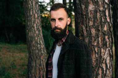 Portre acımasız sakallı hippi adam ormanda balta ile