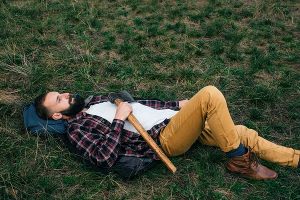 Retrato brutal barbudo hipster hombre en el bosque con hacha —  Fotos de Stock